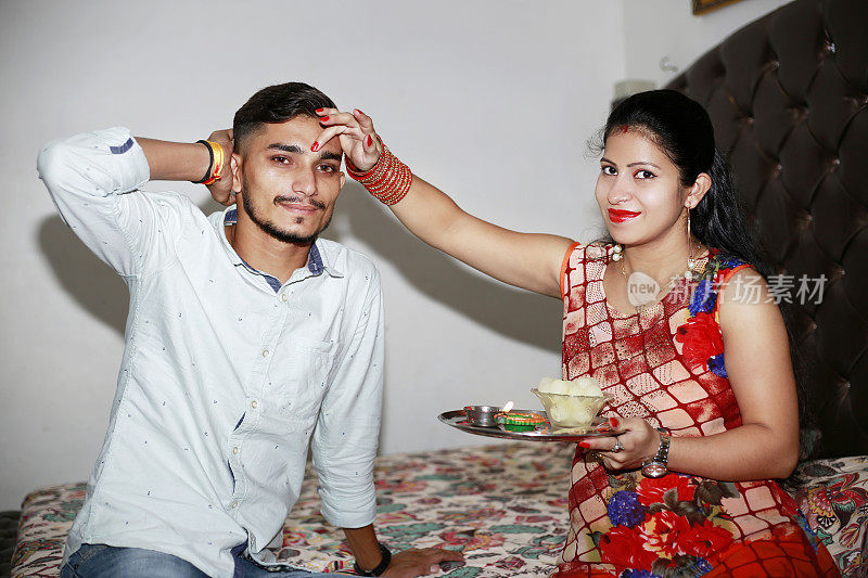 庆祝Bhai Dooj节或Raksha班丹，姐姐在哥哥额头上抹tikka